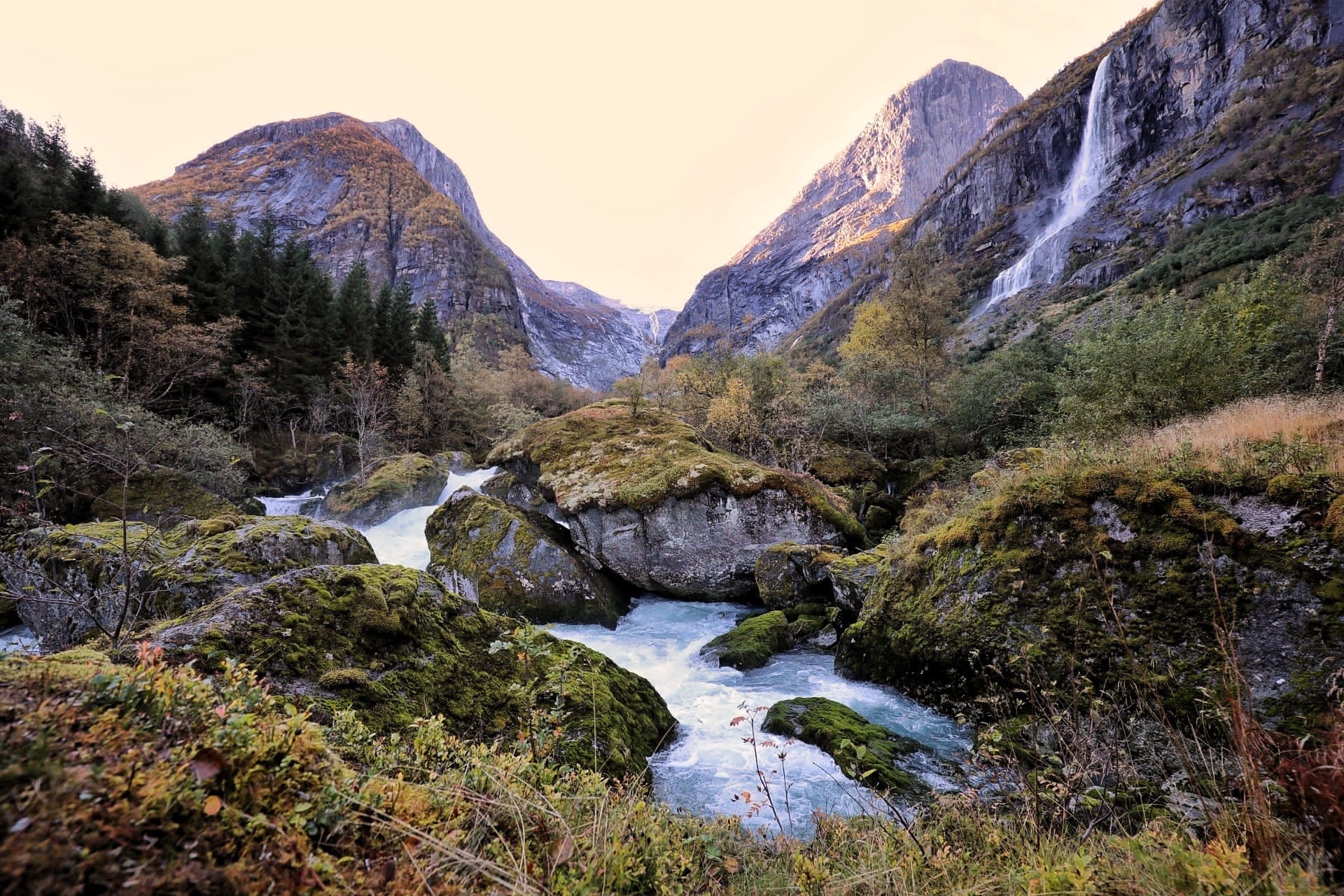 Waterfall and river flowing through a rocky mountain valley.